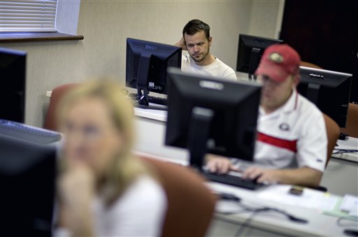In this Aug. 22, 2012 file photo, Scott Marshall, top, of Calhoun, Ga., files for unemployment, in Dalton, Ga. Fewer Americans applied for unemployment benefits last week, and a private survey showed businesses stepped up hiring in August. The data sketched a brighter outlook for the job market one day before the government reports on August employment. (AP Photo/David Goldman, File)
