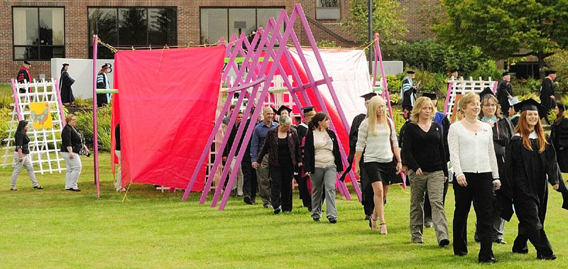 Staff photo by Joe Phelan Rising scholars and the professors who nominated them march across the Campus Green into Convocation on Friday afternoon at the University of Maine at Augusta. The structure, made of wood and tarps, is titled "And the Beet Goes On" in keeping this year's theme of food.