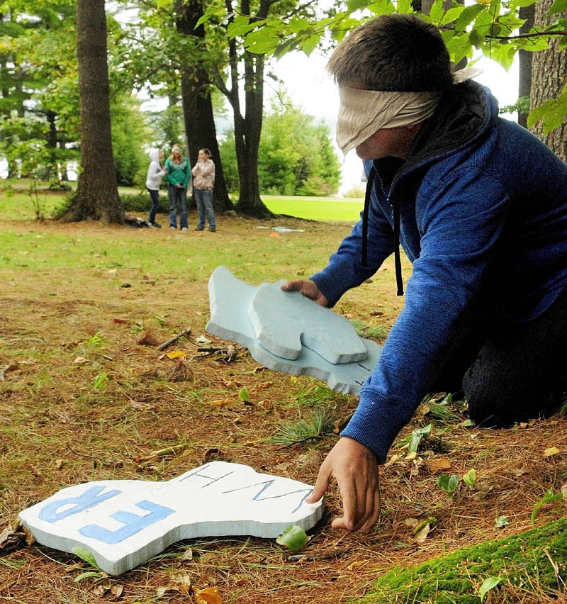 While blindfolded, China Middle School student Joshua Breault finds puzzle pieces with help from teammate in the background who shout out directions to him on Wednesday morning at the State Y camp in Winthrop.