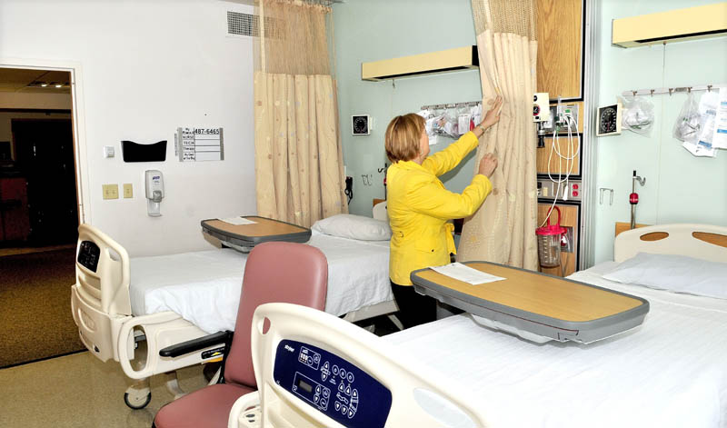 Liisa Janelle, community relations director of Sebasticook Valley Health, draws back a curtain in an existing two-patient room at the Pittsfield hospital. An expansion project should help the hospital to combat infections by transitioning to single-patient rooms with individual bathrooms.