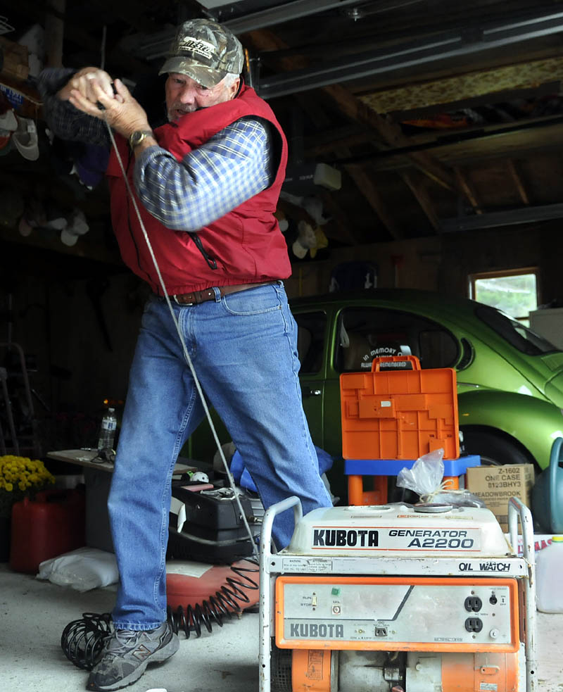 Carroll Whitman attempts to start a generator Monday belonging to his sister, Harriet Blanche, at her Manchester home. The siblings were preparing for the high wind generated by Hurricane Sandy. Whitman, a mechanic, said the mobile electricity supply can be tough to start if they aren’t used often.