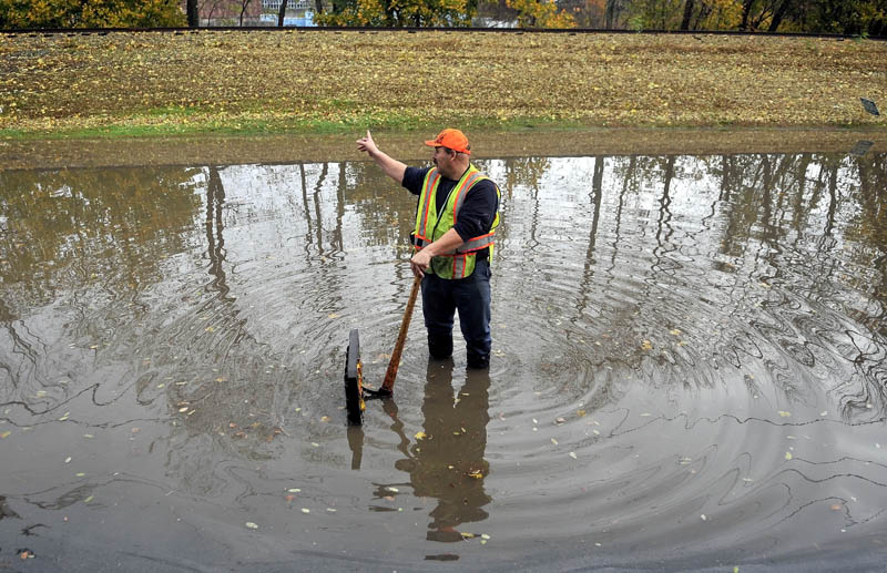 Dave Vigue of the Waterville public works department clears a clogged drain on a flooded Front Street, in front of Joseph's Market, in Waterville after heavy rain on Tuesday.