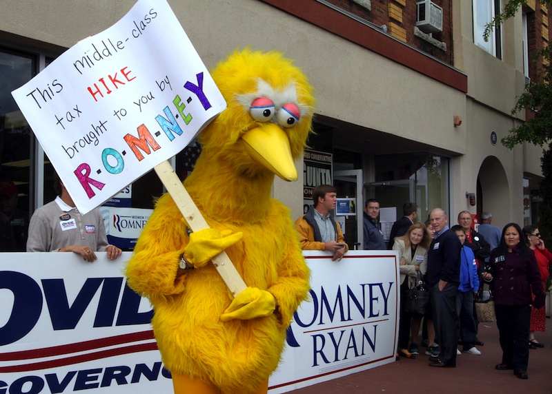 A person dressed up as Big Bird holds a sign against Republican presidential candidate, former Massachusetts Gov. Mitt Romney outside the Romney headquarters, Monday, Oct. 8, 2012 in Derry, N.H. where House Speaker John Boehner of Ohio was about to speak to supporters. (AP Photo/Jim Cole)