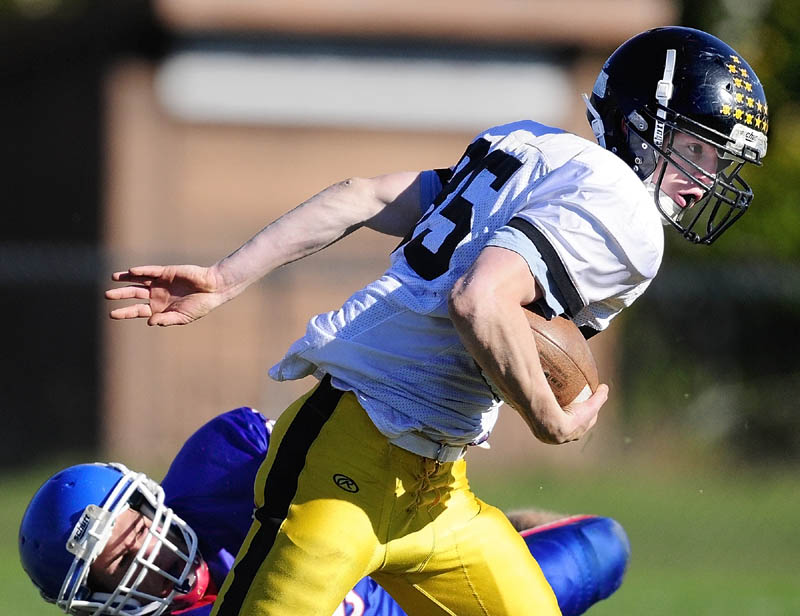 Maranacook running back Logan Emery, top, evades Oak Hill defensive lineman Luke Washburn during a game on Saturday afternoon at Oak Hill High School in Wales.