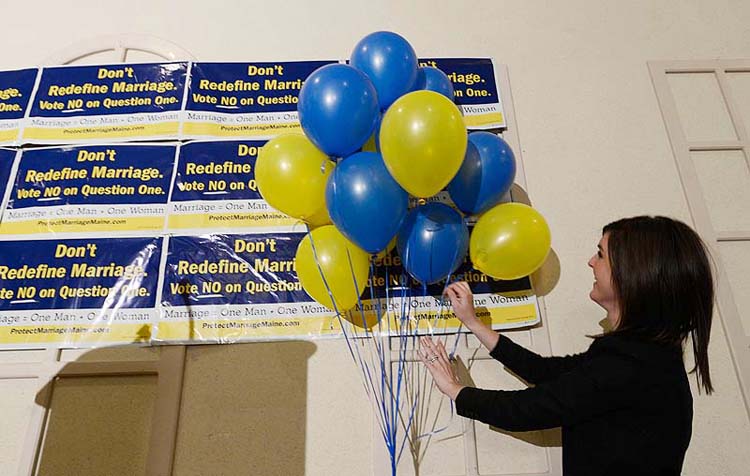 Megan Hutson with Protect Marriage Maine sets up the stage at the Ramada Conference Center in Lewiston on Tuesday.