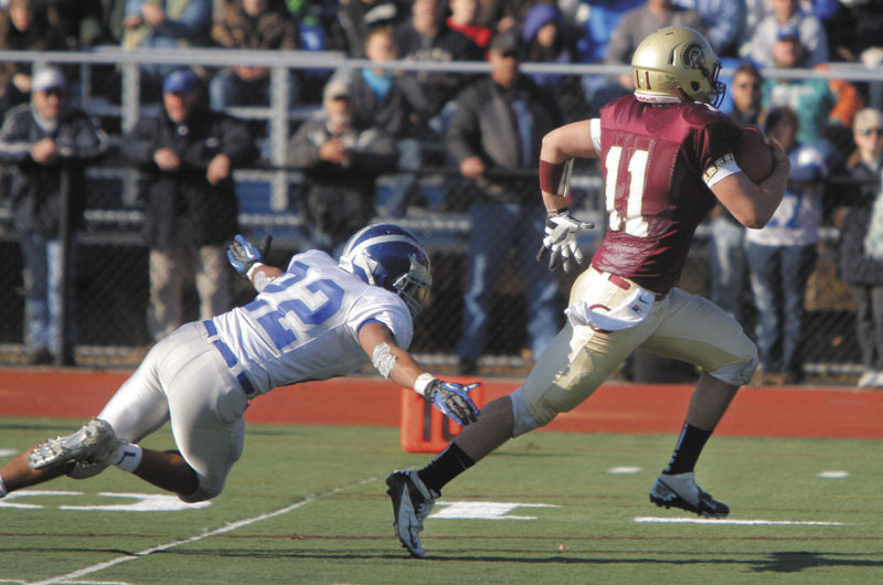 Thornton Academy quarterback Eric Christensen pulls away from Xavier Lewis of Lawrence to score a touchdown in the third quarter for the Trojans in the Class A state football championship on Saturday at Fitzpatrick Stadium in Portland. Thornton won, 37-23.