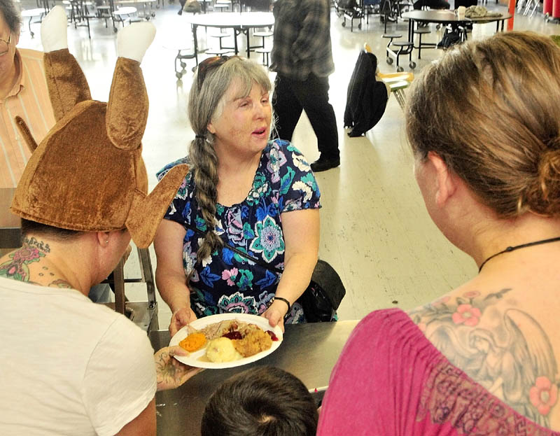 Sally Dill, center, takes her Thanksgiving dinner back to her seat on Thursday morning at Gardiner Area High School.