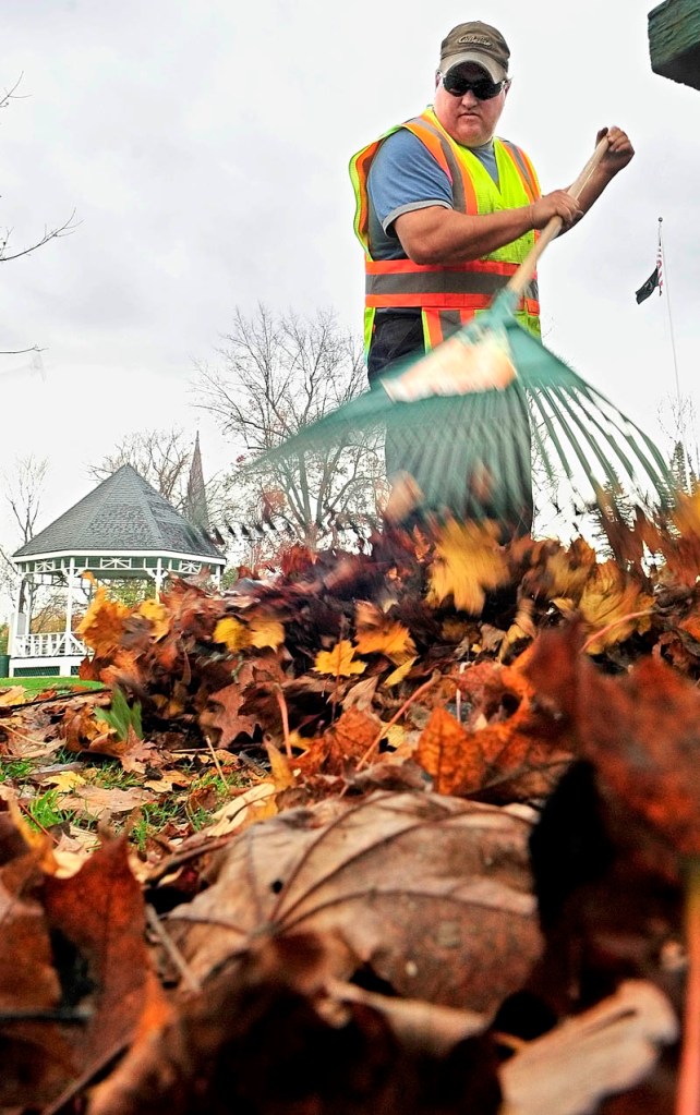 Gardiner city worker Pat Chadwick rakes leaves towards tube that sucks them into a truck on Wednesday afternoon. He was part of a crew cleaning up leaves on the Gardiner Common.