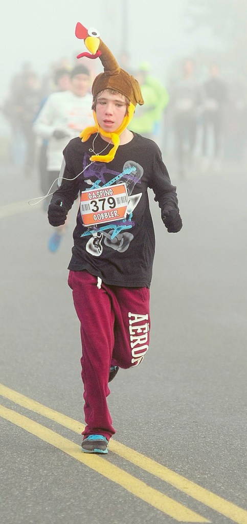 Evan West, of Manchester, wears a turkey while he runs in the Gasping Gobbler 5K race on Thursday morning that started and ended at Cony High School in Augusta. There were over 400 finishers in the annual Thanksgiving day race that gave food for prizes. The first male and female finisher got a trophy and full Thanksgiving dinner. In the each age group, the prizes were a turkey for first place, pie for second place and then dinner rolls for third.