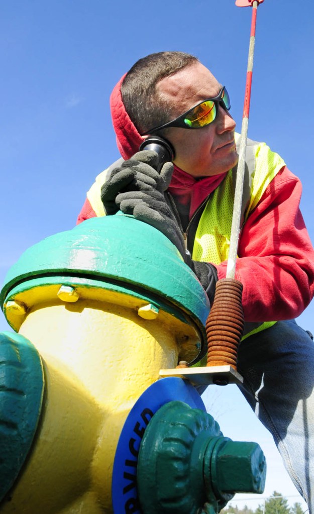 Aaron Scalia, of the Greater Augusta Utilities District, uses an earpiece to listen to double-check that no water is running inside a hydrant that had been winterized earlier by another crew.