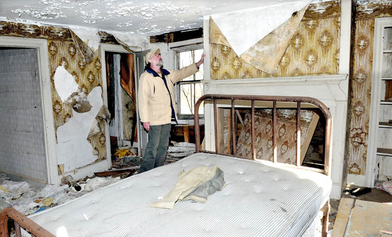 Bob Hubbard examines the hearth around a fireplace in the John Wentworth home, built in 1800 in Athens. The home has not been lived in for decades and may be torn down next year.