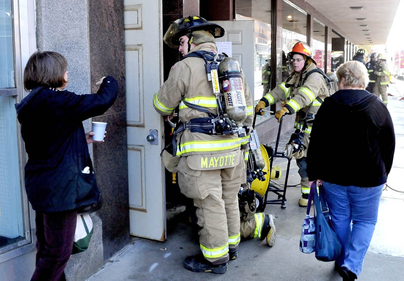 Maine Made & More shop employees Becky Turly, left, and Susan Begin, speak with Waterville firefighters, who were setting up fans to ventilate portions of The Center building, after a strange odor was detected on Monday. The building was evacuated and Main Street shut down for about two hours.