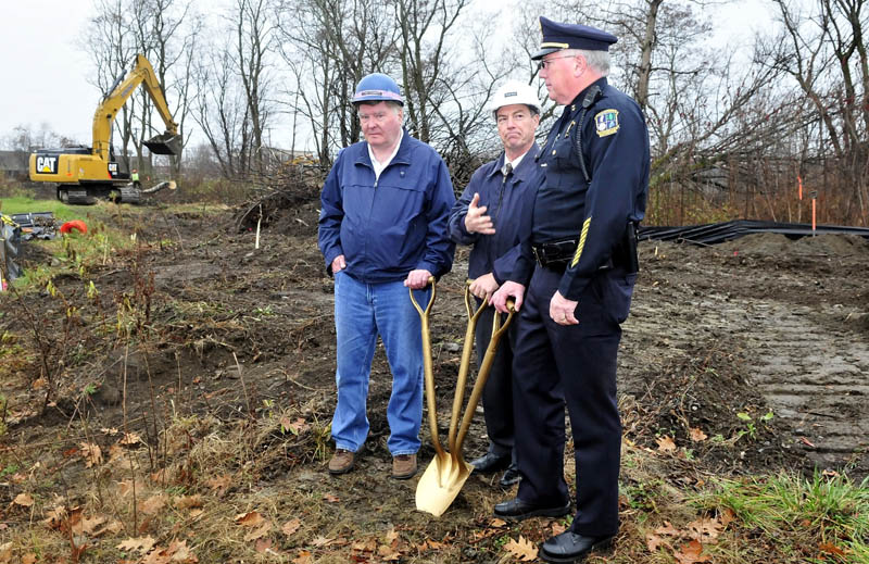 As workers remove trees in background, Waterville City Manager Michael Roy, center, motions to Police Chief Joseph Massey during a groundbreaking ceremony at the site of the new police department at Colby Circle on Tuesday. At left is City Councilor Fred Stubbert.