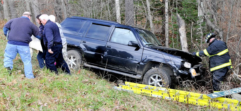 Winslow firefighters escort Anita Ward, of Winslow, away from the vehicle she was driving, which went off the Garland Road and slammed into a tree, on Sunday.