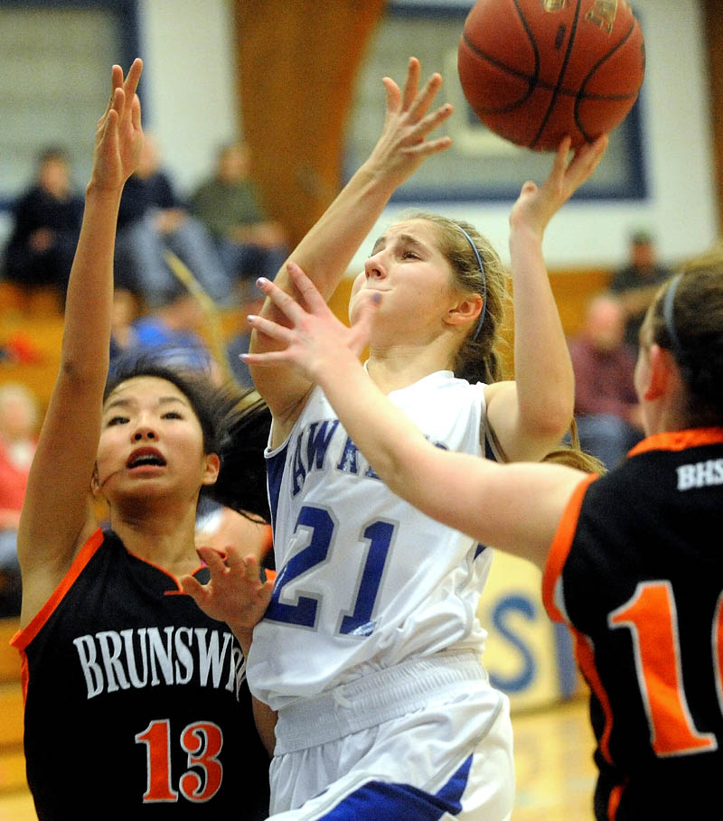 Lawrence High School's Dominique Lewis, center, drives to the hoop and draws the foul as Brunswick High School Gillian Doehring, left, and Emily Black, 10, right try to defend her in the first quarter Tuesday at Lawrence High School in Fairfield.