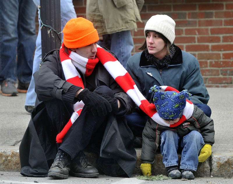 Steven Woodman shares his scarf with his son Tristram, 3, as mother Darlene Woodman sits in the background, at the Chester Greenwood Day parade in downtown Farmington Saturday.