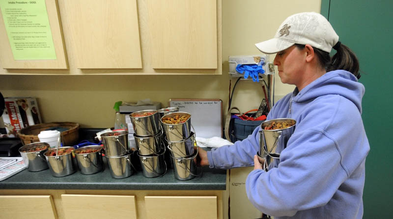 Casey Foss prepares dinner for the 20 dogs housed at the Humane Society Waterville Area, on Webb Road in Waterville, Friday. Hundreds of bags of dog and cat food and nearly $10,000 have been donated to the shelter in the past couple of weeks.