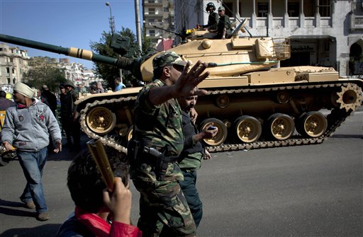 An Egyptian Army officer detains a man who was attacked by protesters gathering near the presidential palace during overnight clashes between supporters and opponents of President Mohammed Morsi in Cairo.