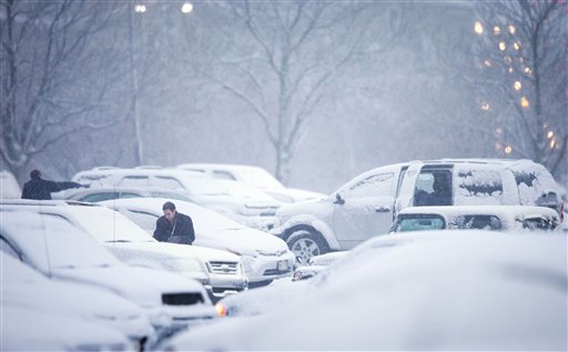 Mutual of Omaha employees clean their vehicles of snow before leaving on their drive home during the evening commute on Wednesday in Omaha. A storm that has dumped more than a foot of snow in the Rocky Mountains is heading east and is forecast to bring the first major winter storm of the season to the central plains and Midwest.