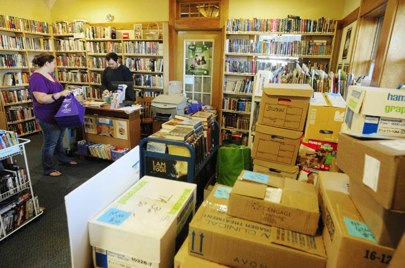 Gina Davis, left, checks out books from library assistant Jared Bond on Thursday at the Belgrade library.