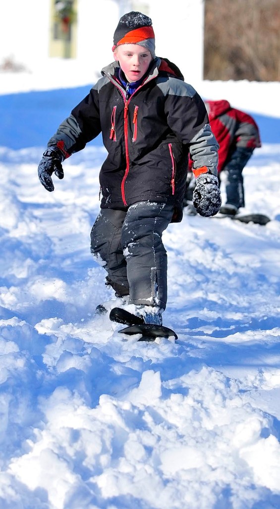 Ryan Gray, 8, of Hallowell, snowboards down a small hill on Friday, in Hallowell. He and his brother, Finn Gray, were trying out their Christmas presents the day after a snowstorm.
