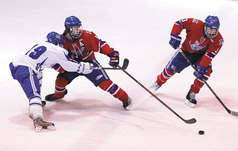 PASSING THE PUCK: Messalonskee High School’s Dominic Dexter passes the puck to teammate Joshua Towle, right, while getting checked by Lawrence High School’s Jack Flynn during the first period of Wednesday night’s game at Sukee Arena in Winslow.