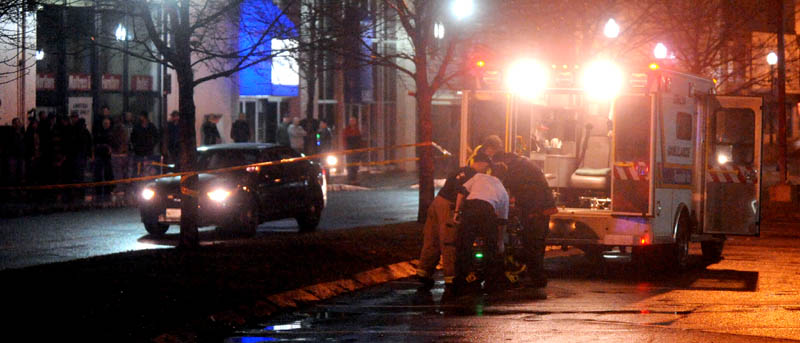 Staff photo by Michael G. Seamans The victim of a shooting is loaded into an ambulance on The Concourse in Waterville late Tuesday night.