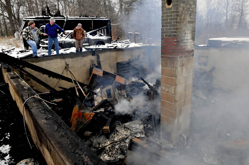 Homeowner Mike Smith, center, speaks with Cornville Fire Chief Ken Hogate, left, and neighbor Dale Emery, as smoke rises from the remains of his home, which was destroyed by fire on Monday.