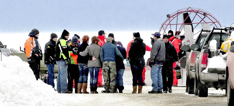 People seen hugging and holding each other approach Maine Warden Service personnel wearing survival suits, at the boat launch on Rangeley Lake on Monday. The body of Dawn Newell was recovered earlier in the day after her snowmobile went through the ice Sunday night.