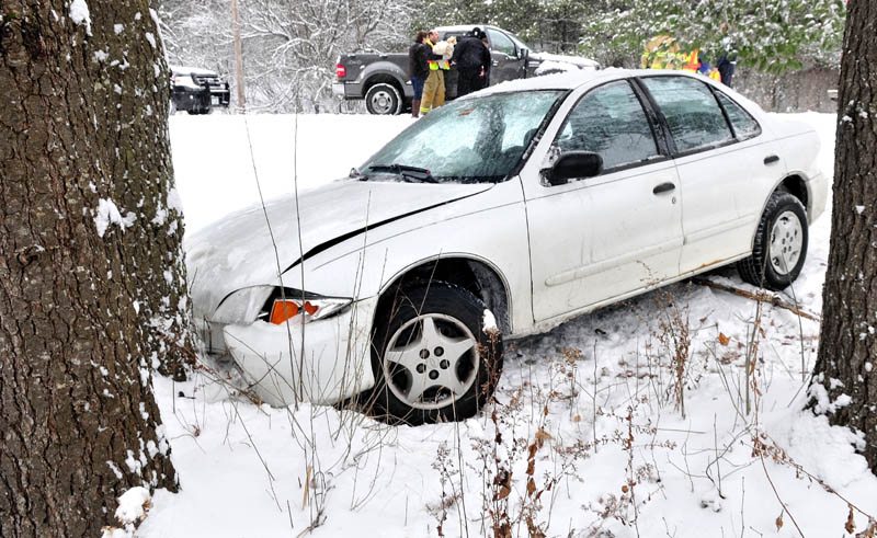 A Winslow firefighter cradles a dog as rescuers help an injured driver out of a vehicle that slid off snow-covered Route 100 in Winslow on Monday. The dog was a passenger in the vehicle and escaped injury.