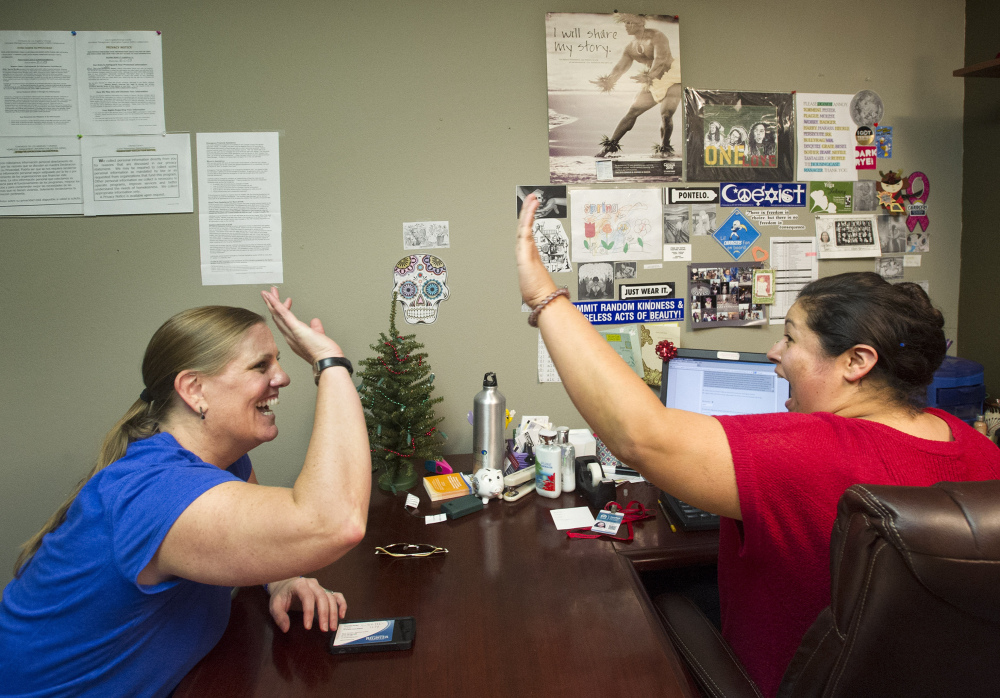 Lisa Donlea, left, and Susan Roberts, a certified enrollment officer, celebrate after working on Donlea’s federal health insurance exchange enrollment online in Laguna Beach, Calif., last week. Jan. 1 marks the start date for one of the centerpieces of the Affordable Care Act: insurance plans offered by private companies through either federal or state-run marketplaces, or exchanges.