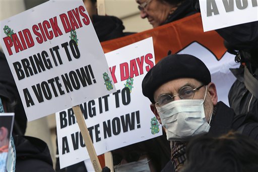 Activists hold signs Friday during a rally at New York's City Hall to call for immediate action on paid sick days legislation in light of the continued spread of the flu. An unusually early and vigorous flu season is drawing attention to the cause that has both scored victories and hit roadblocks in recent years: mandatory paid sick leave.