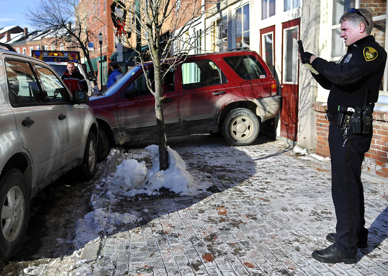 Gardiner Police Officer Dan Murray photographs a SUV that accidentally backed into a building owned by the Bank of Maine Thursday, on Water Street in Gardiner. The operator briefly lost control of the vehicle due to a medical condition, Murray said, before striking the building, a parked vehicle and light pole. The driver was examined by Gardiner rescue but didn't warrant additional medical attention, Murray said. The building sustained minimal damage.