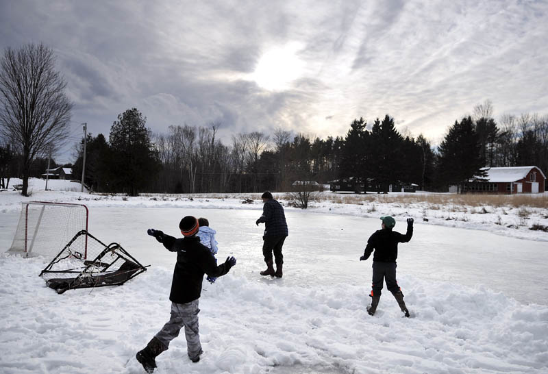 Boys pelt Mike Flynn, center, with snowballs on Sunday, on the ice at Lily Pond in West Gardiner. The ice that Flynn was cleaning off with a shovel was too rough for hockey, so the kids resorted to plugging him with snow.