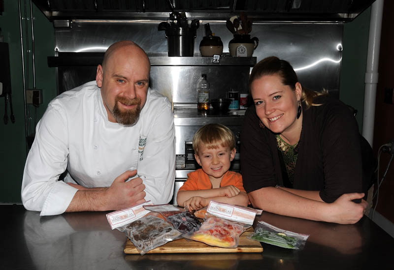 Mark and Kelly LaCasse with their 3-year old son, Eben, pose for a picture with a selection of frozen, gourmet cuisine at their 4 Madison Ave. location in Skowhegan on Friday.