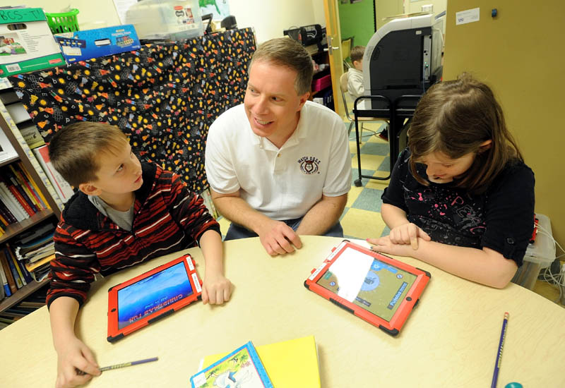 Chris Rhoda, center, a volunteer with Watch DOGS, a group of dads that volunteer at Belgrade Central School, sits with students Brandon Denardo, 8, left, and Isabell Frost, 9, in Belgrade on Friday. The group of volunteers was created to provide more of a male presence at school.