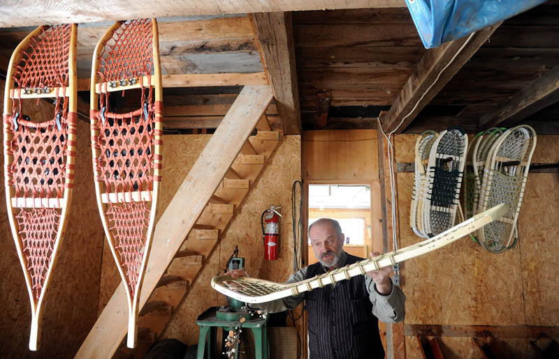 Dave Giampetruzzi, 63, of China, explains the difference of the Maine Guide snowshoe compared to the traditional designs, hanging on the left, in the workshop at Pine Grove Lodge in Bingham on Thursday.