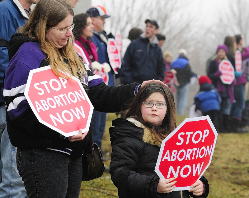 Christina Biegeleisen, left, and her daughter, Makayla Biegeleisen, 8, both of South Paris, hold signs on the east side of the State House during Hands Around the Capitol event on Saturday in Augusta.