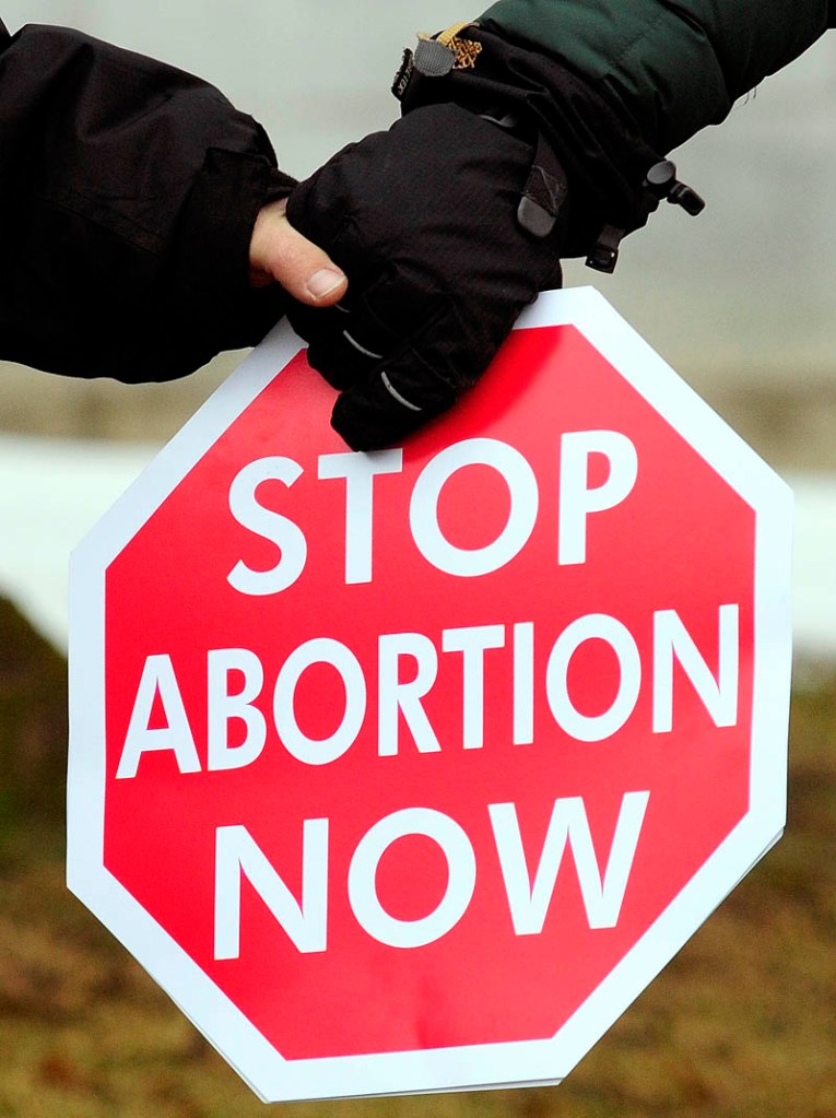 Anti-abortion protesters hold hands and a sign on the east side of the State House during Hands Around the Capitol event on Saturday in Augusta.
