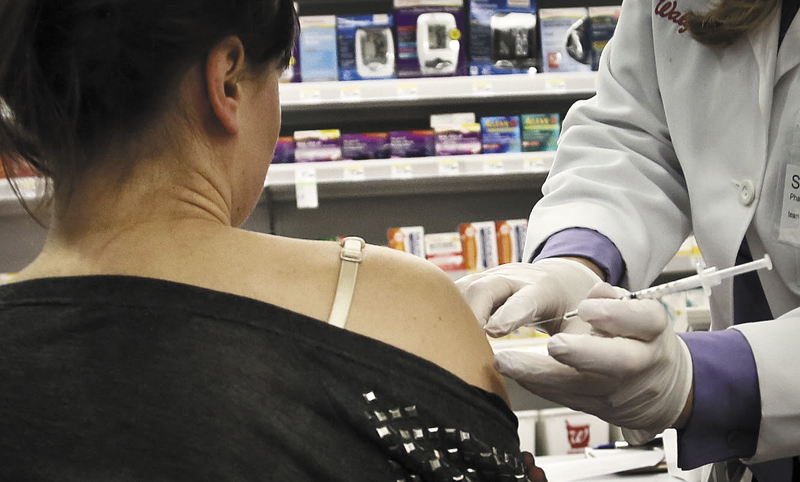 Pharmacist Stacia Woodcock, a pharmacy manager for Walgreens in New York, administers a flu vaccine Monday.