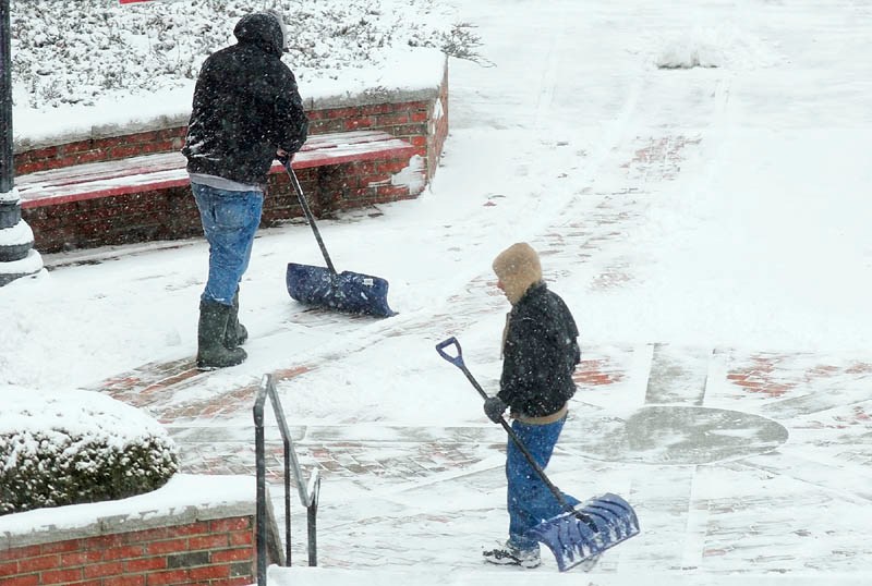 Workers shovels snow on Wednesday Jan. 16, 2013 in front of Key Plaza in downtown Augusta.