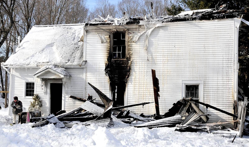 Mikey Raley exits the burned New Portland home of her daughter, Shellen Raley Masterman, carrying salvaged photo albums.