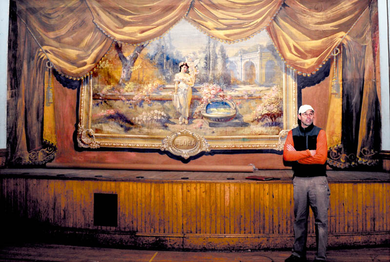 Builder Stephen Dionne speaks about restoring the former Skowhegan Grange in front of a hand-painted curtain, on the stage in the Grand Assembly Room, on Wednesday.