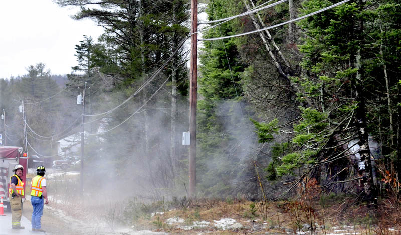 Winslow firefighters monitor a fallen tree leaning against a power line on China Road on Thursday morning. The tree smoked at the top where it hit the lines and at the base where the electricity was grounded.