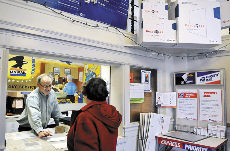 Hallowell Post Master Ed Boutin assists customer Joan Haig Wednesday at the counter. The US Postal Service is ending Saturday letter delivery in August.