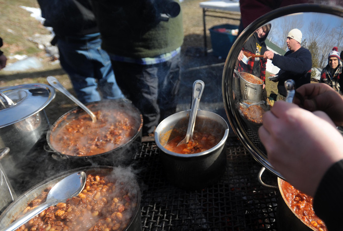 Brad Houghton is reflected in the pot lid as he serves a sample of his chili at the annual chili cookoff at the Winter Carnival at Lake George, on the Skowhegan and Canaan town line, on Saturday.
