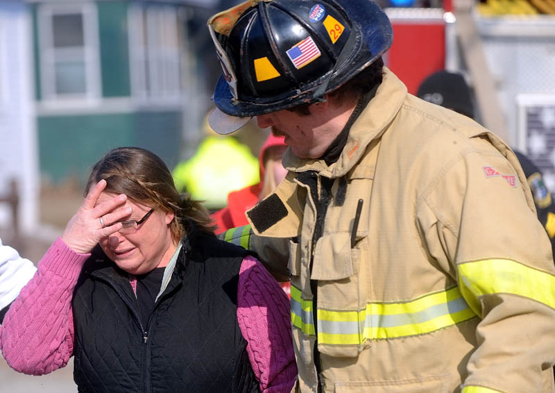 Kimberly Guite, 46, is comforted by Lt. Scott Holst, right, as her rental home burns on Squire Street in Waterville Thursday.