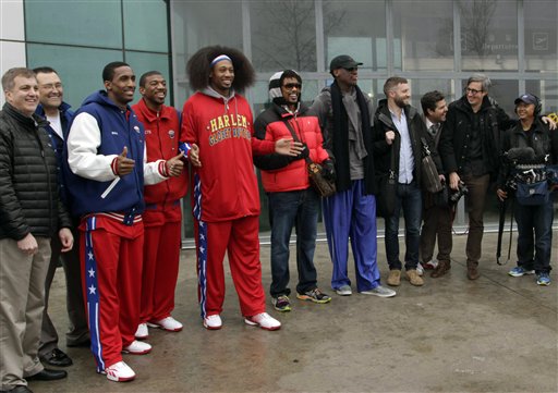 Flamboyant former NBA star Dennis Rodman, fifth from right, poses with three members of the Harlem Globetrotters basketball team, in red jerseys, and a production crew for the media upon arrival at Pyongyang Airport, North Korea, Tuesday, Feb. 26, 2013. Rodman known as "The Worm" arrived in Pyongyang, becoming an unlikely ambassador for sports diplomacy at a time of heightened tensions between the U.S. and North Korea. (AP Photo/Kim Kwang Hyon)