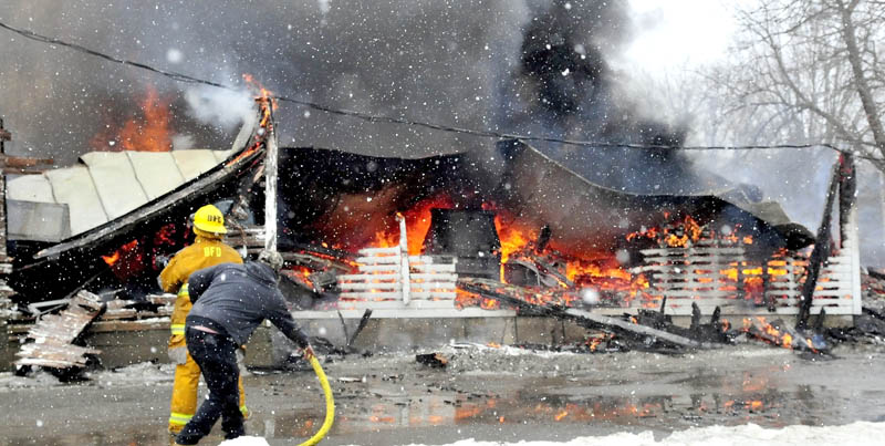 Firefighters attack flames at the rear storage area of an apartment building that was destroyed by fire on Main Street in Unity on Saturday morning. The building is owned by Ralph Nason. Sr.