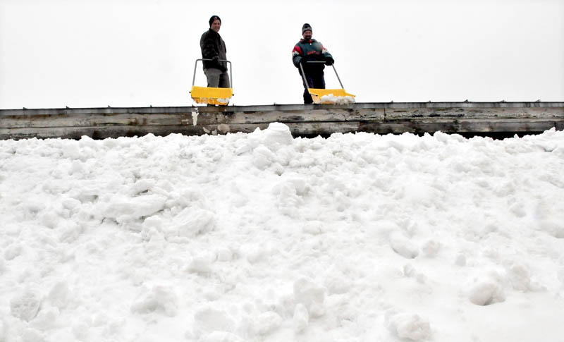 The falling rain added weight to the roof of Madison Mattress and Furniture store on Thursday, so Andy Deuble, left, and Kevin McLain shoveled off the heavy load.